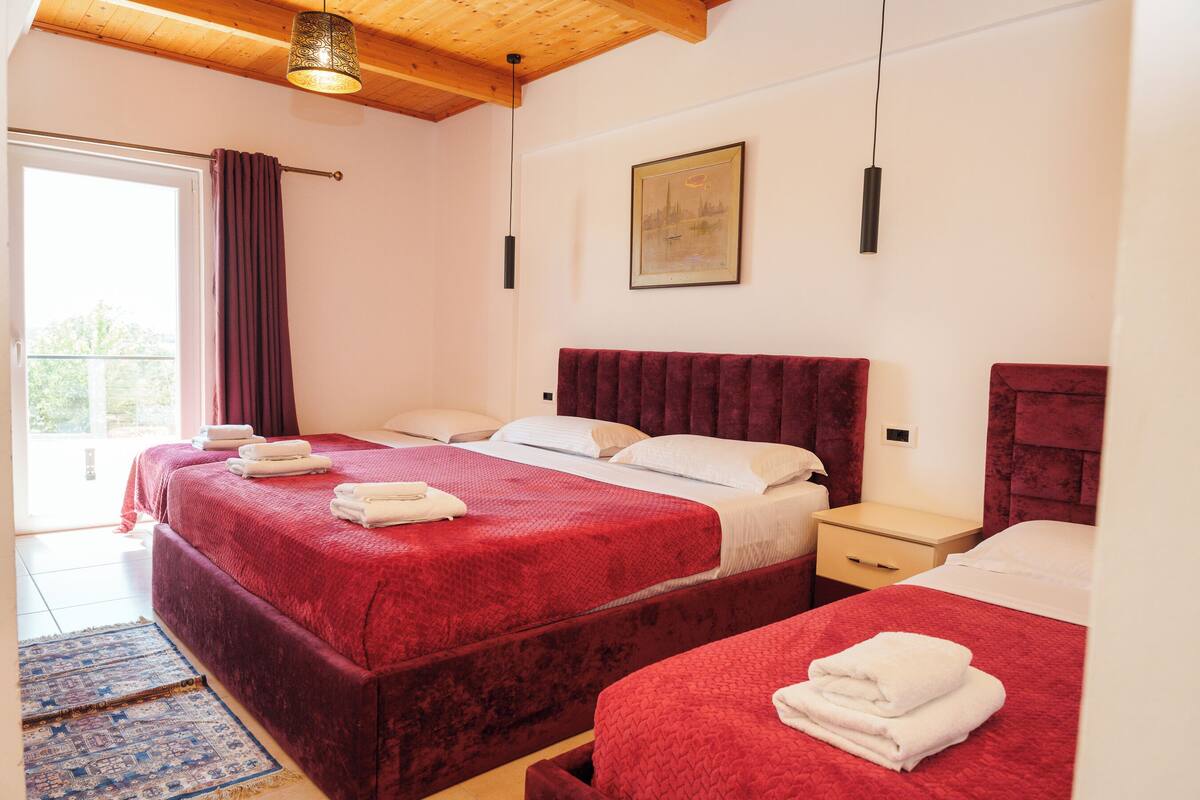 Habitació d'hotel amb dos llits, un finestral gran, un quadre a la paret i una làmpada al sostre.