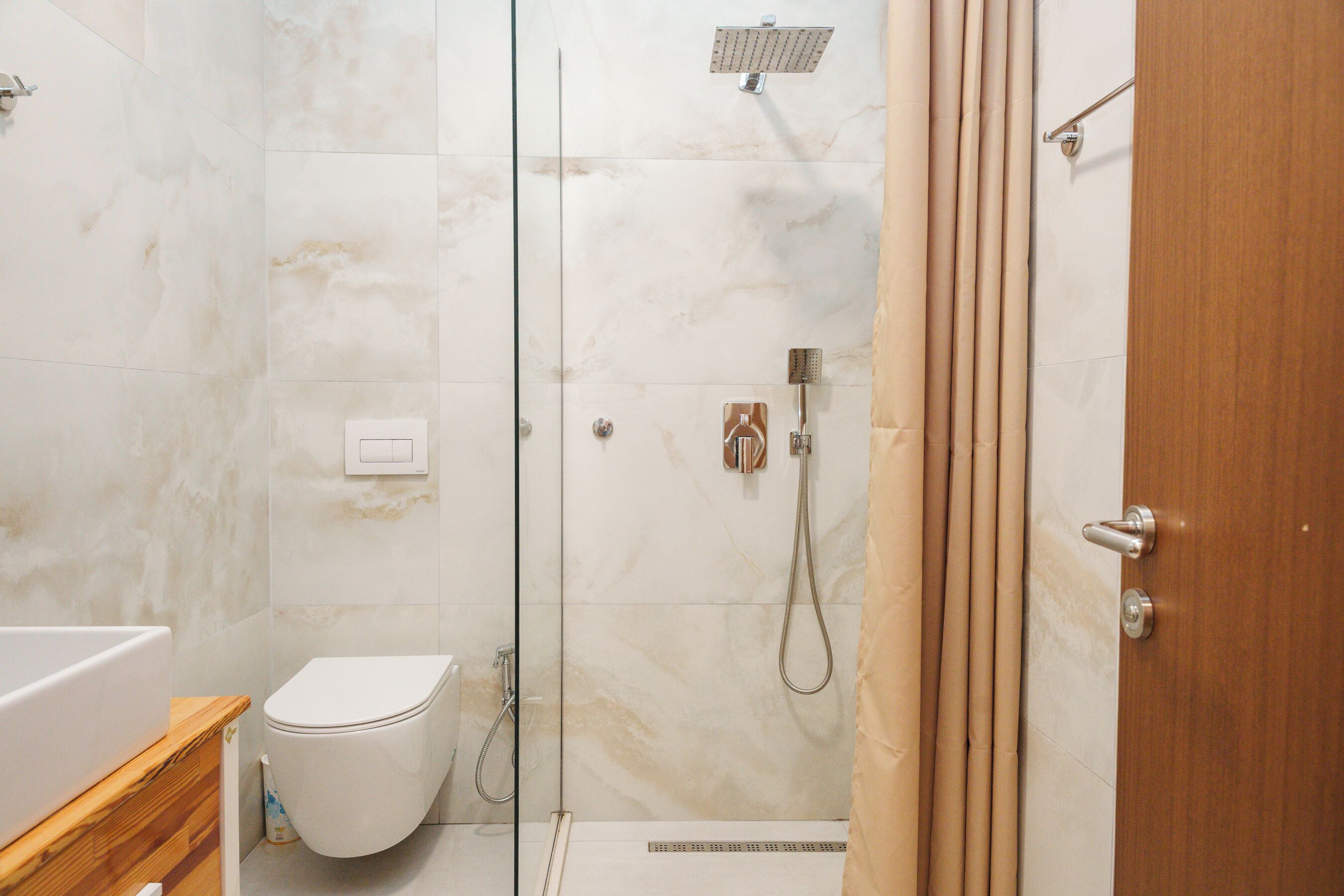 Un baño con ducha de vidrio, inodoro y tocador de madera.