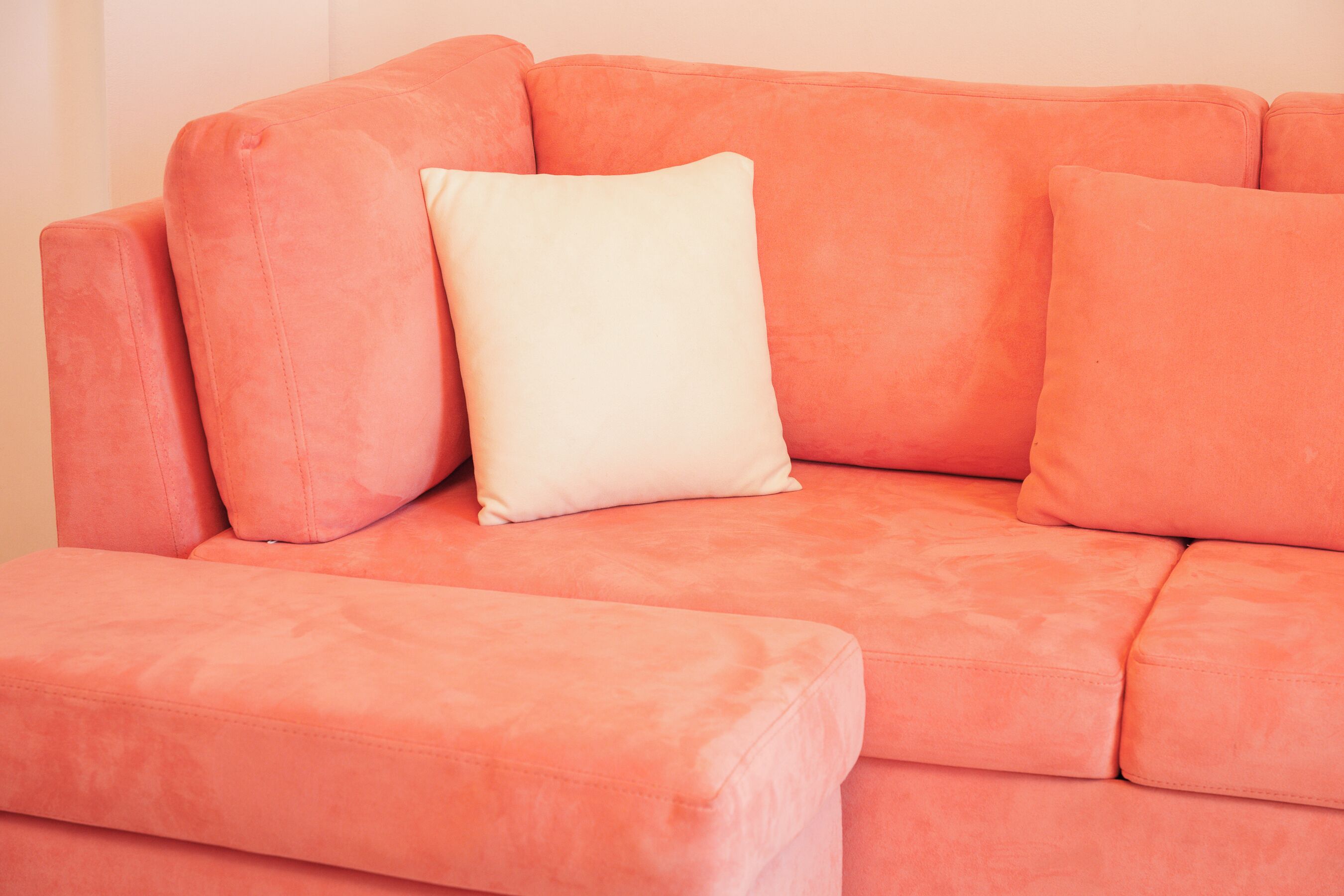 Un canapé rose avec un coussin blanc.