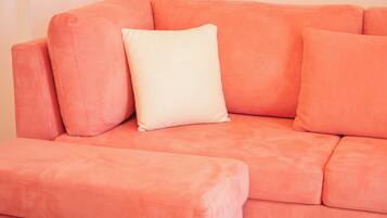 Un canapé rose avec un coussin blanc.