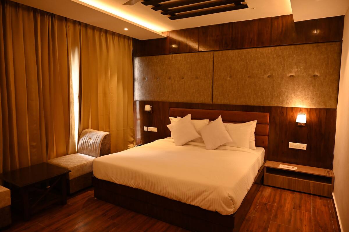 Ein Hotelzimmer mit einem großen Bett, einem Nachttisch, einem Sessel und einem Holzkopfteil.