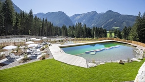 A swimming pool with a wooden deck, surrounded by a wooden fence, and a view of mountains in the background. - Chalet in Neukirchen near Anfängerpiste (Neukirchen)