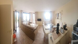 Ein gemütlicher Wohnbereich mit Sofa, Esstisch, Fernseher und Küchenzeile.