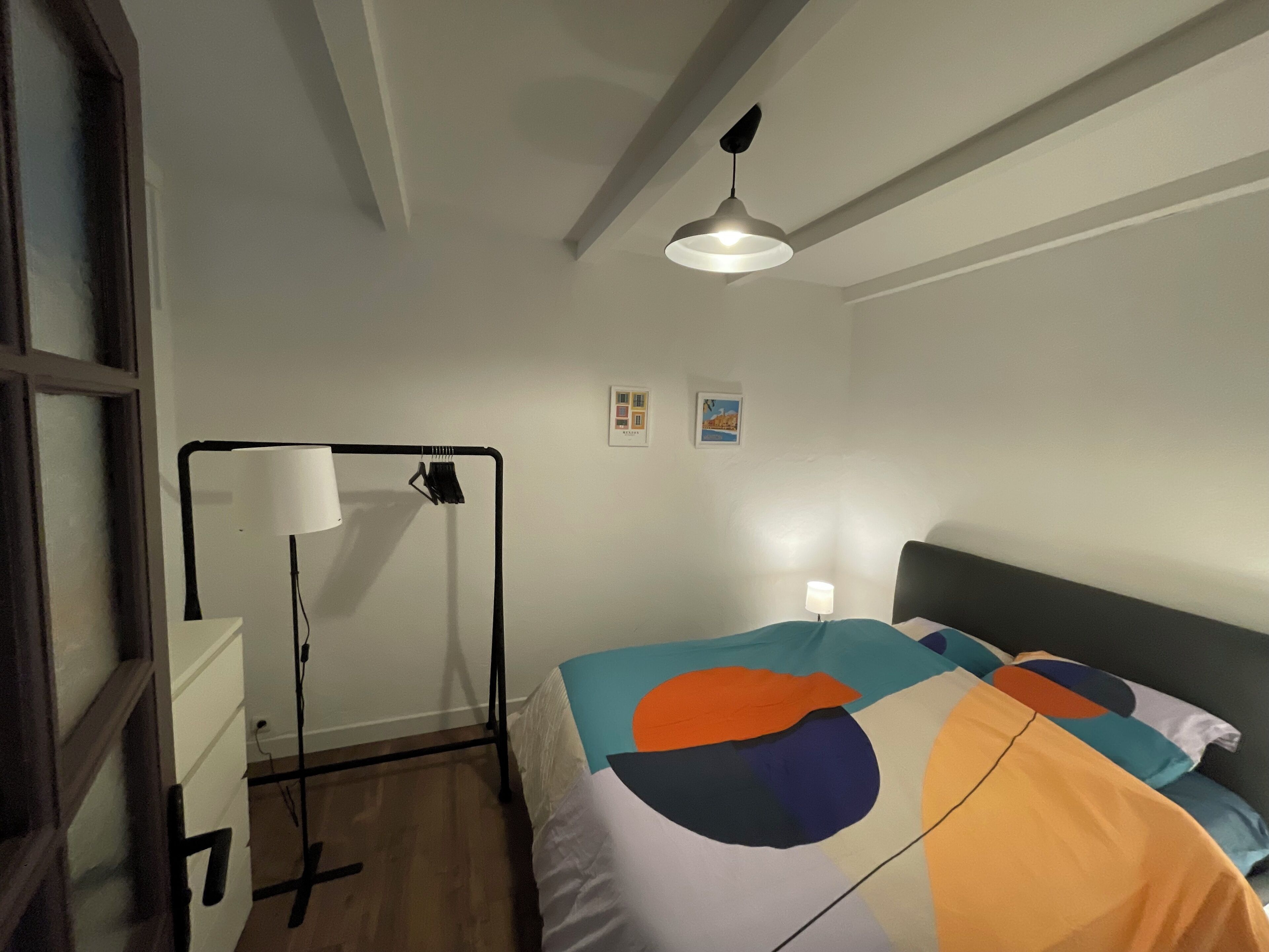 A bedroom with a bed, a desk, a lamp, and a ceiling fan.