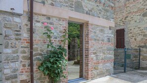 A stone building with a doorway, a metal gate, and a rose bush.