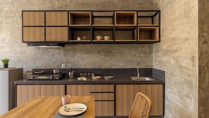 Una cocina moderna con armarios de madera, encimera negra y comedor con mesa y sillas de madera.
