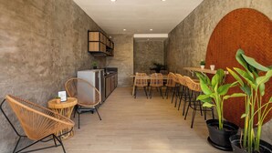 Un interior moderno con comedor, sillas de mimbre, cocina y plantas en macetas.