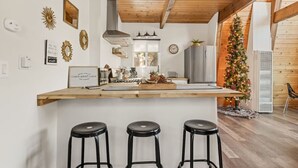 Eine Küche mit Holzbalkendecke, einer zentralen Kochinsel mit Barhocker, einem Kühlschrank und einem Weihnachtsbaum.