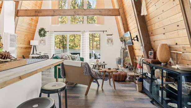 Ein gemütlicher Loftraum mit hohen Decken, Holzbalken, einem Essbereich und einer Küche mit schwarzem Arbeitsplatz.