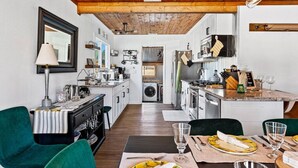 A compact kitchen with modern appliances, a dining area with a table set for two, and a cozy seating arrangement.