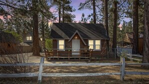 A small cabin with a porch, surrounded by trees.
