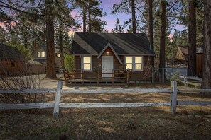 Une petite cabane dotée d’un porche, entourée d’arbres.