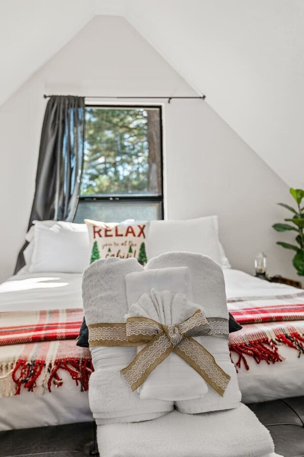 A bedroom with a bed, a window, a pillow with 'RELAX' text, and a towel with a bow.