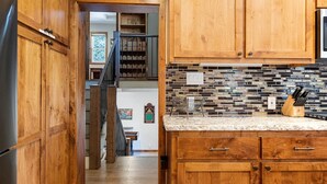 A kitchen with wooden cabinets, a tiled backsplash, and a marble countertop.