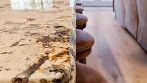A kitchen with a marble countertop and stools.