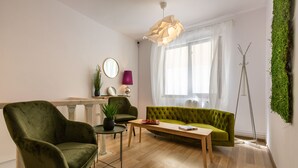 A modern living room with a green sofa, a green armchair, a wooden coffee table, and a floor lamp. - Lagom Hotel (Bucharest)