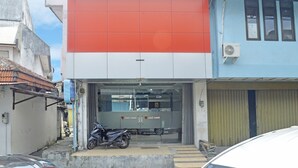 A building with a large red and white facade, a motorcycle parked in front, and a closed garage door.