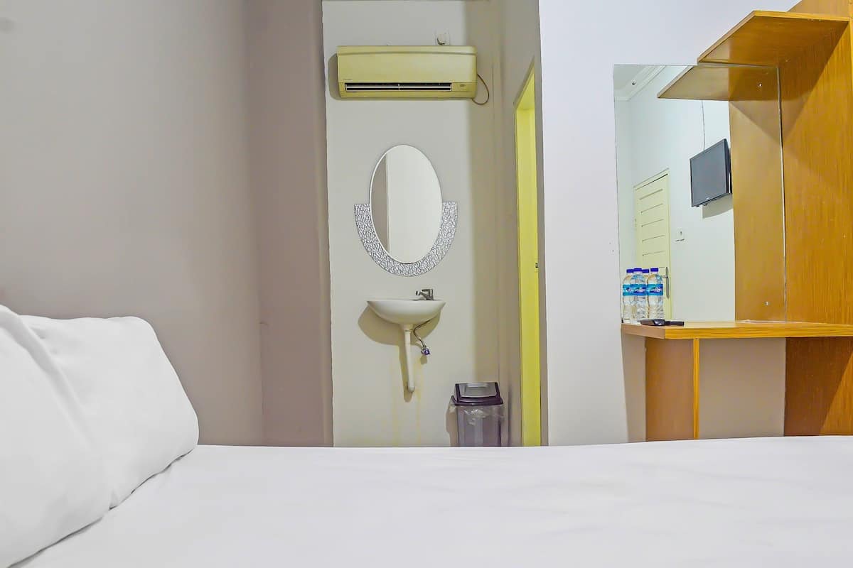 Una habitación de hotel con cama, lavamanos, espejo y equipo de aire acondicionado.