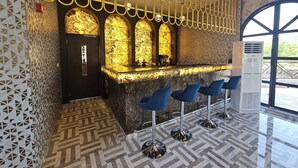 A bar area with a marble countertop, blue bar stools, and a patterned floor.