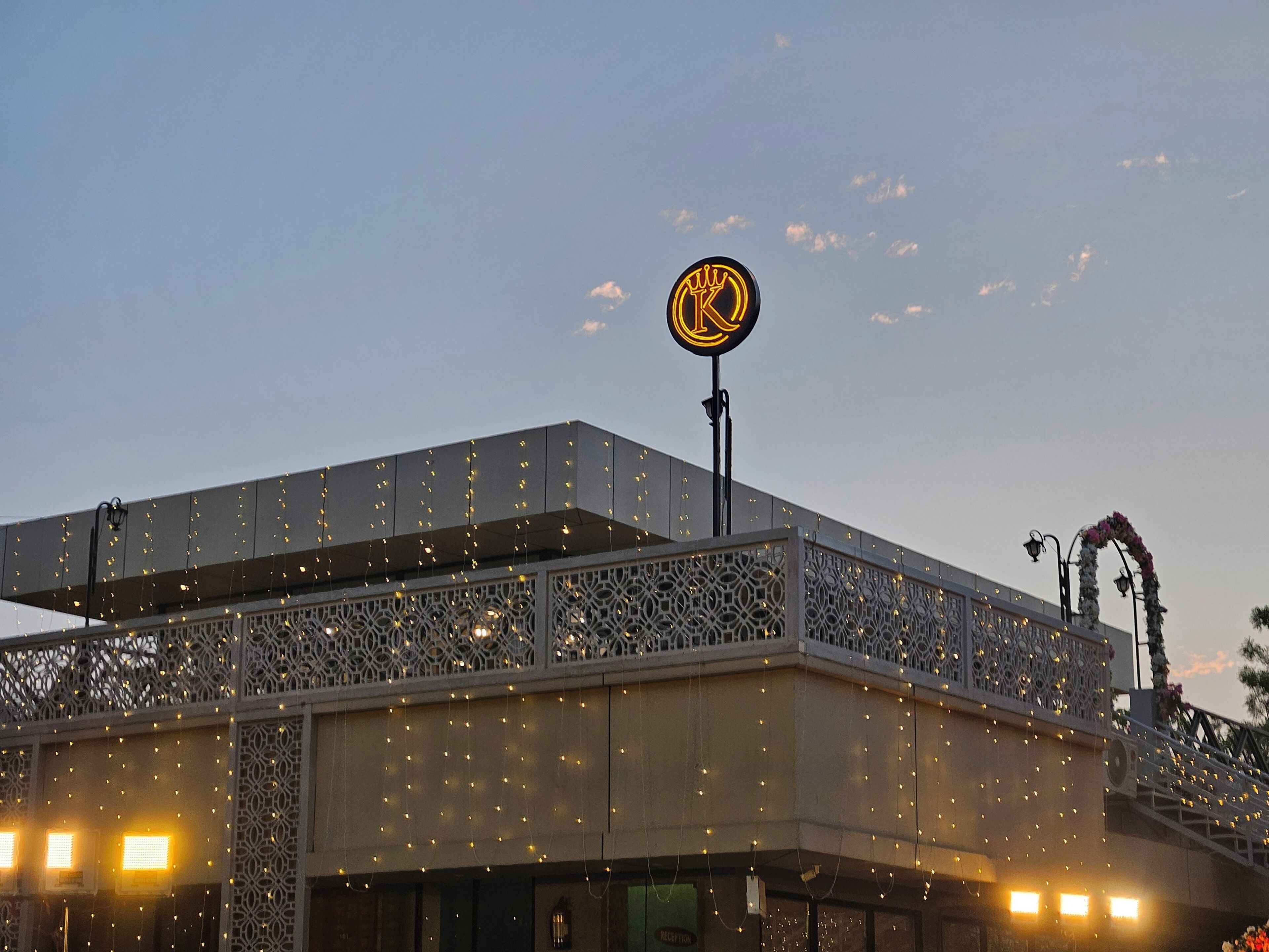 A building with a large illuminated sign, decorative string lights, and a balcony with intricate lattice work.