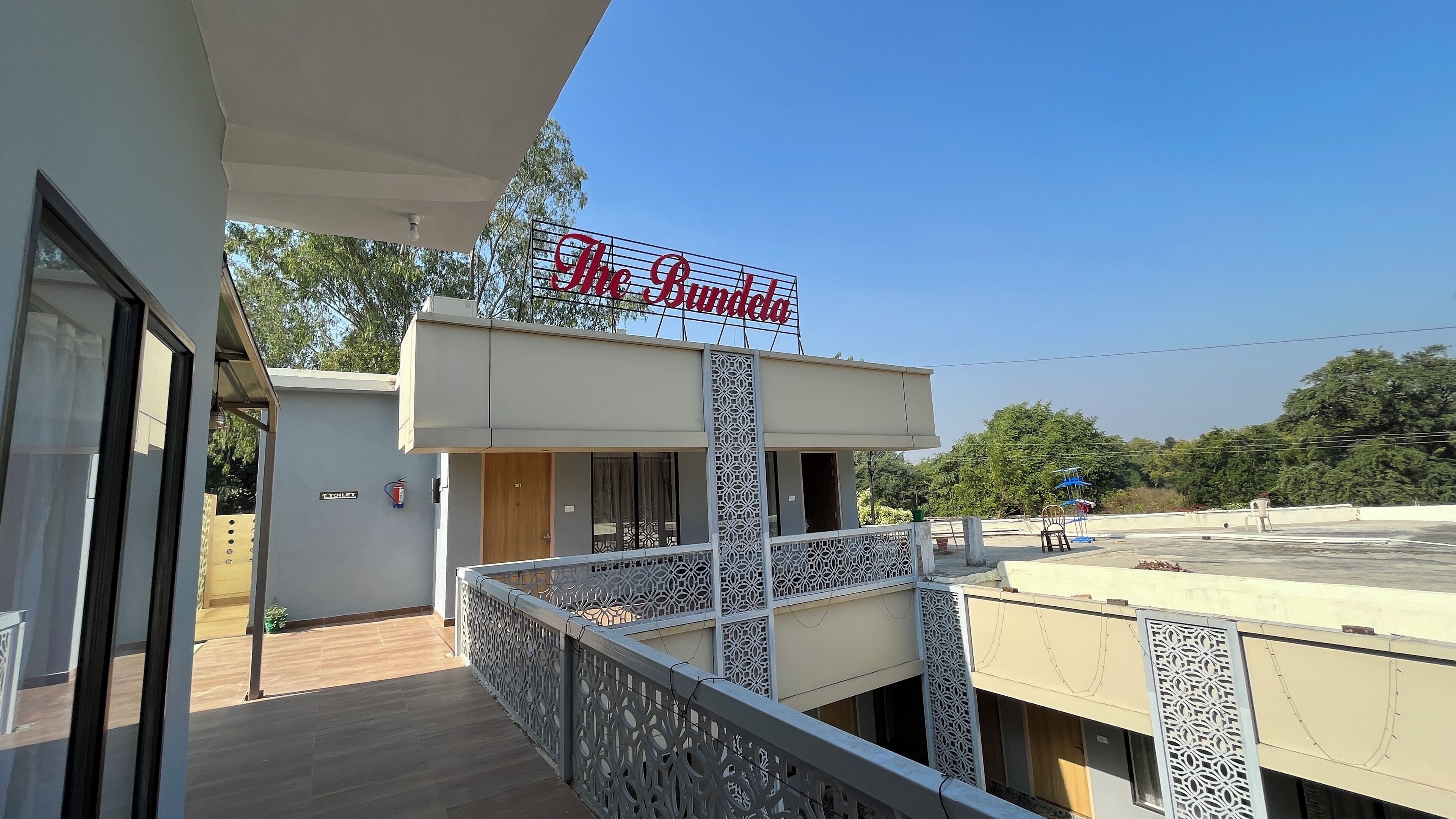 A hotel named "The Bundela" with a balcony, a wooden door, and a signboard.