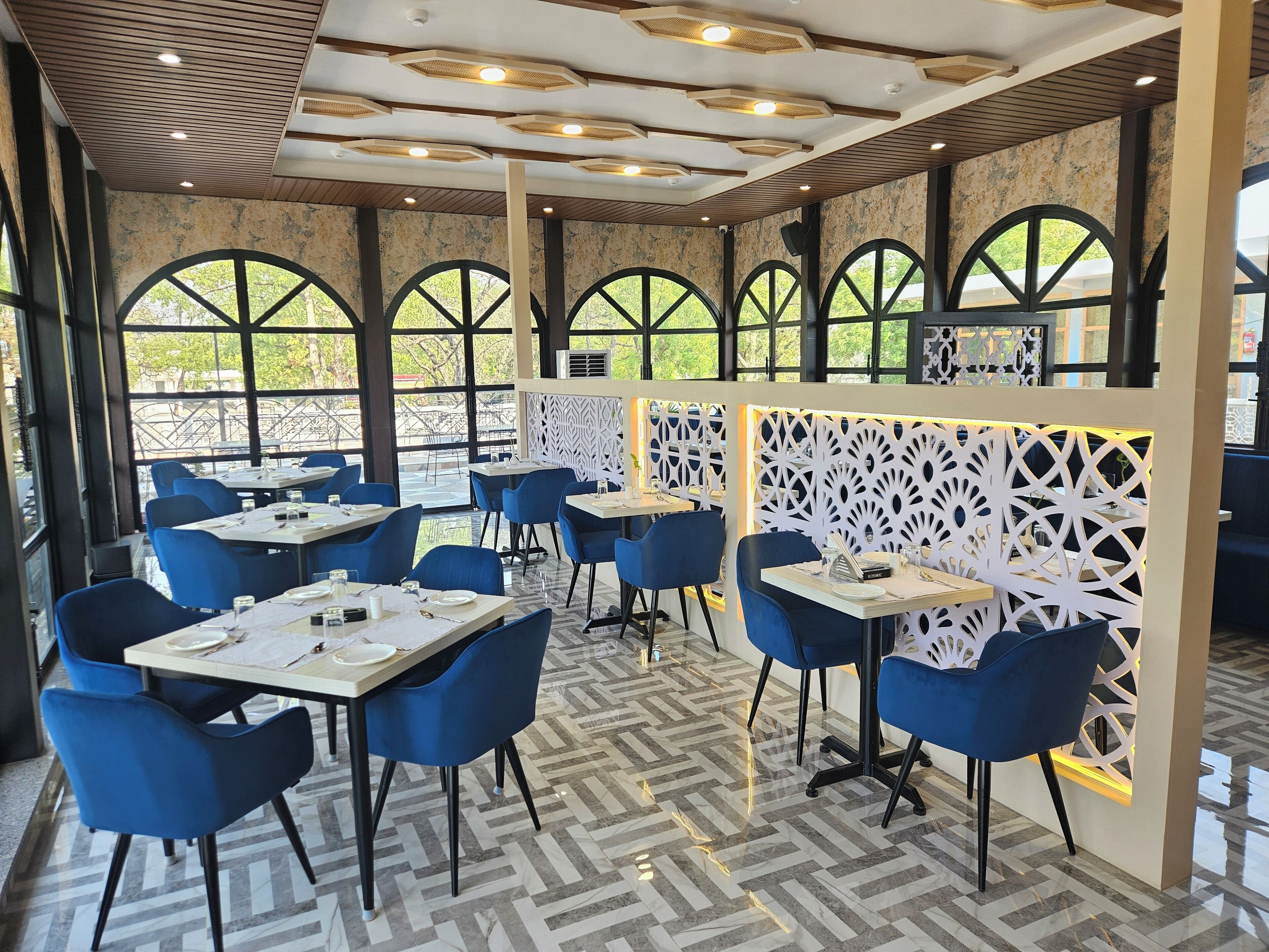 Un restaurant avec des chaises et des tables bleues, et un sol à motifs.