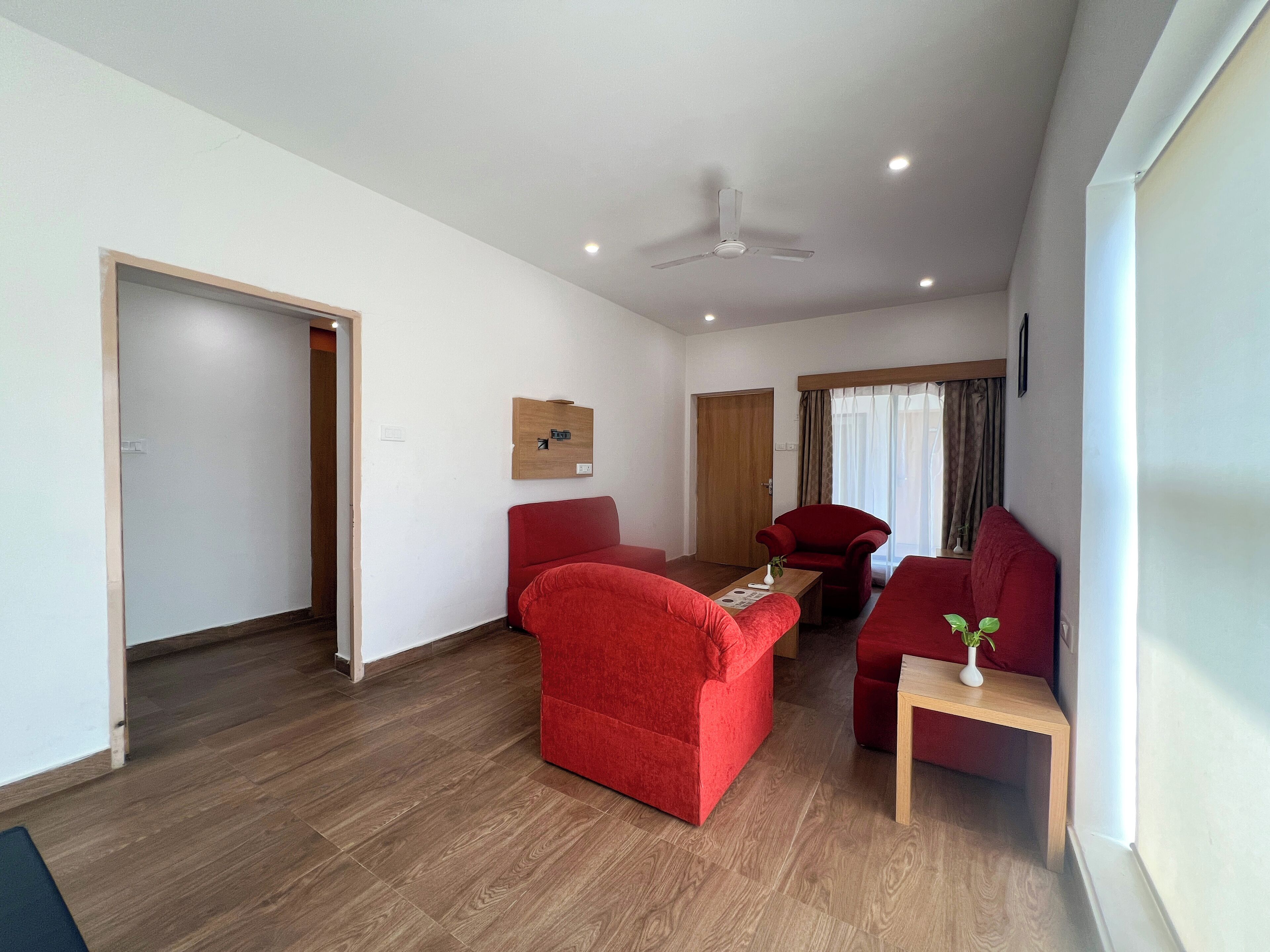 Un salon moderne avec un plancher en bois, un ventilateur de plafond et des meubles rouges.