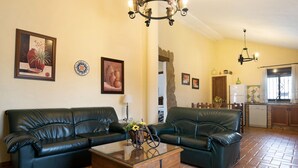 Sala de estar com dois sofás de couro preto, uma mesa de centro de vidro e uma mesinha de cabeceira de madeira com um vaso.