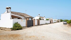 Rua residencial com casas, entrada de automóvel em cascalho e um carro estacionado.