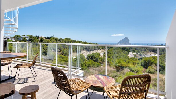 A balcony with wicker furniture, a spiral staircase, and a view of the coastline. - Apartment 'Real De Ifach - Atico' with Sea View, Wi-Fi and Air Conditioning (Calpe)