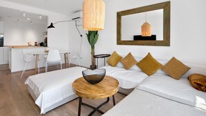 A modern living room with a sofa, a round wooden table, and a hanging light fixture. - Apartment 'Real De Ifach - Atico' with Sea View, Wi-Fi and Air Conditioning (Calpe)