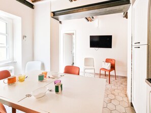 A room with a white table, chairs, a TV, and a door.