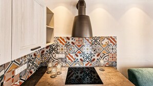 A kitchen with patterned tiles, a built-in stove, and a wooden cabinet.