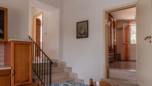 Un comedor con una mesa lista para dos personas, una escalera y un pasillo que lleva a otra habitación.