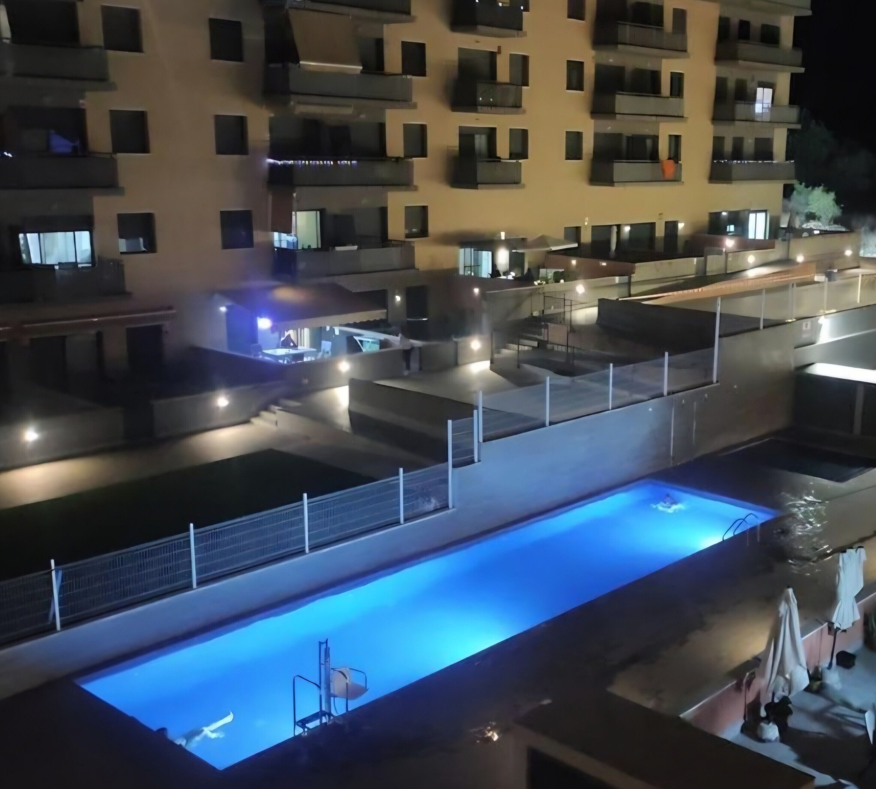 Un immeuble résidentiel à plusieurs étages doté de balcons, d’une piscine et d’espaces de détente en plein air.