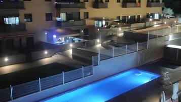 Un immeuble résidentiel à plusieurs étages doté de balcons, d’une piscine et d’espaces de détente en plein air.
