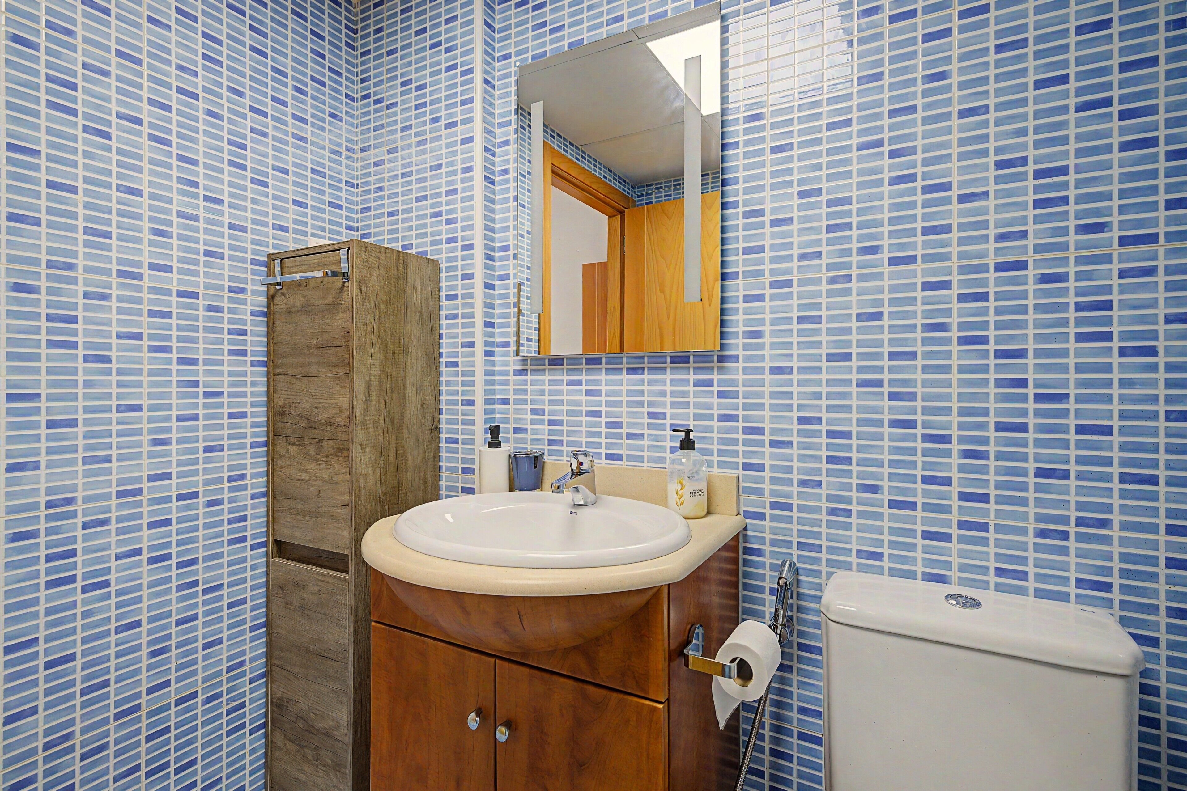 Un baño con un mueble de madera, un lavabo y un inodoro.