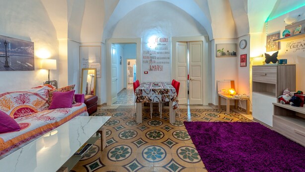 Un amplio salón con una mesa de comedor, un sofá y una alfombra morada.