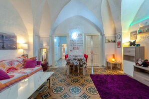 A spacious living area with a dining table, a sofa, and a purple rug.