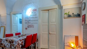 Un comedor con una mesa cubierta por un mantel estampado, sillas rojas y una pared con citas inspiradoras.