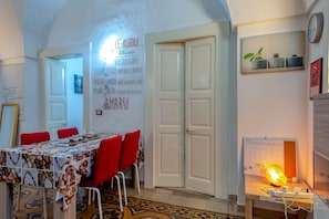 A dining area with a table covered in a patterned tablecloth, red chairs, and a wall with motivational quotes.