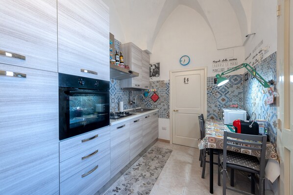 A compact kitchen with a built-in oven, a sink, and a dining area with a table and chairs.