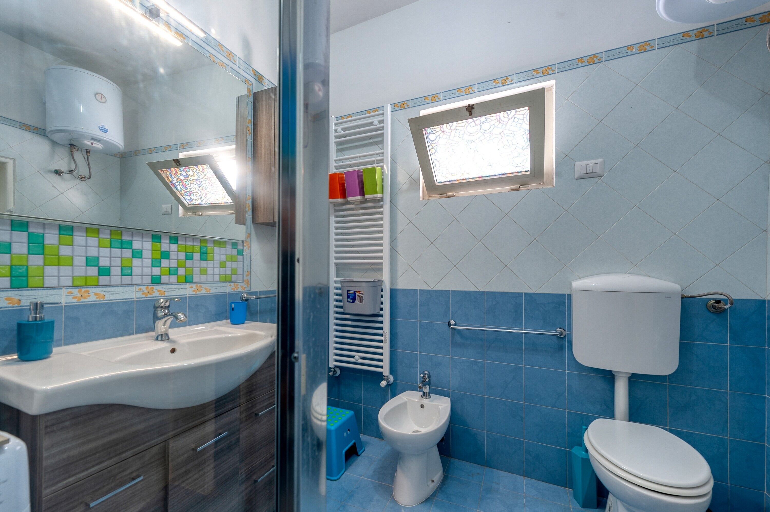 A bathroom with a sink, bidet, toilet, and a window with a view.