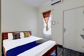 Une chambre d’hôtel avec un lit, une fenêtre avec des rideaux, une porte et un appareil de climatisation.