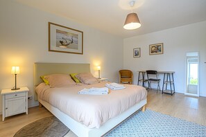 Un dormitorio con cama, mesitas de noche, un escritorio y sillas.