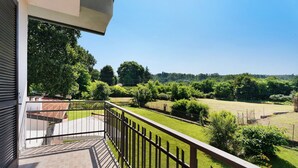 Un balcon donnant sur un paysage verdoyant et des arbres.