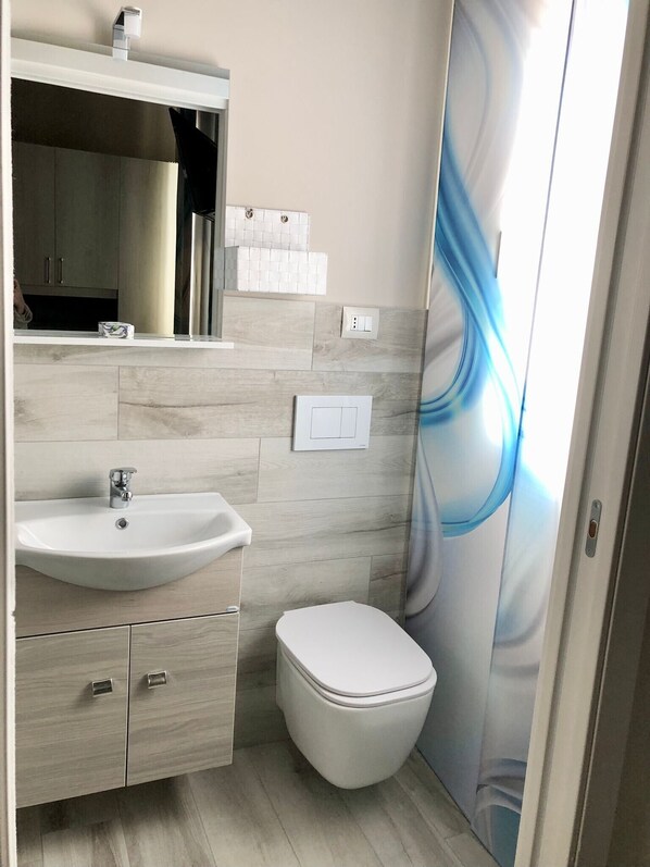 Une salle de bain avec un lavabo, des toilettes et un miroir.