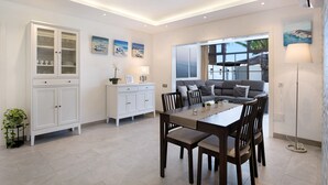 Een moderne woonkamer met een eethoek, een witte kast en een groot raam met uitzicht.