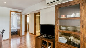 A modern living room with a flat-screen TV on a wooden stand, a glass-fronted cabinet with dishes, and a hallway leading to a bedroom. - Apartment "Olga" with Private Terrace and Wi-Fi (Platja d'Aro)