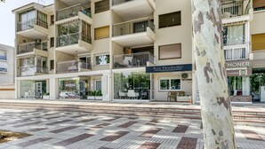 A multi-story building with balconies, a café, and a visible storefront. - Apartment "Olga" with Private Terrace and Wi-Fi (Platja d'Aro)
